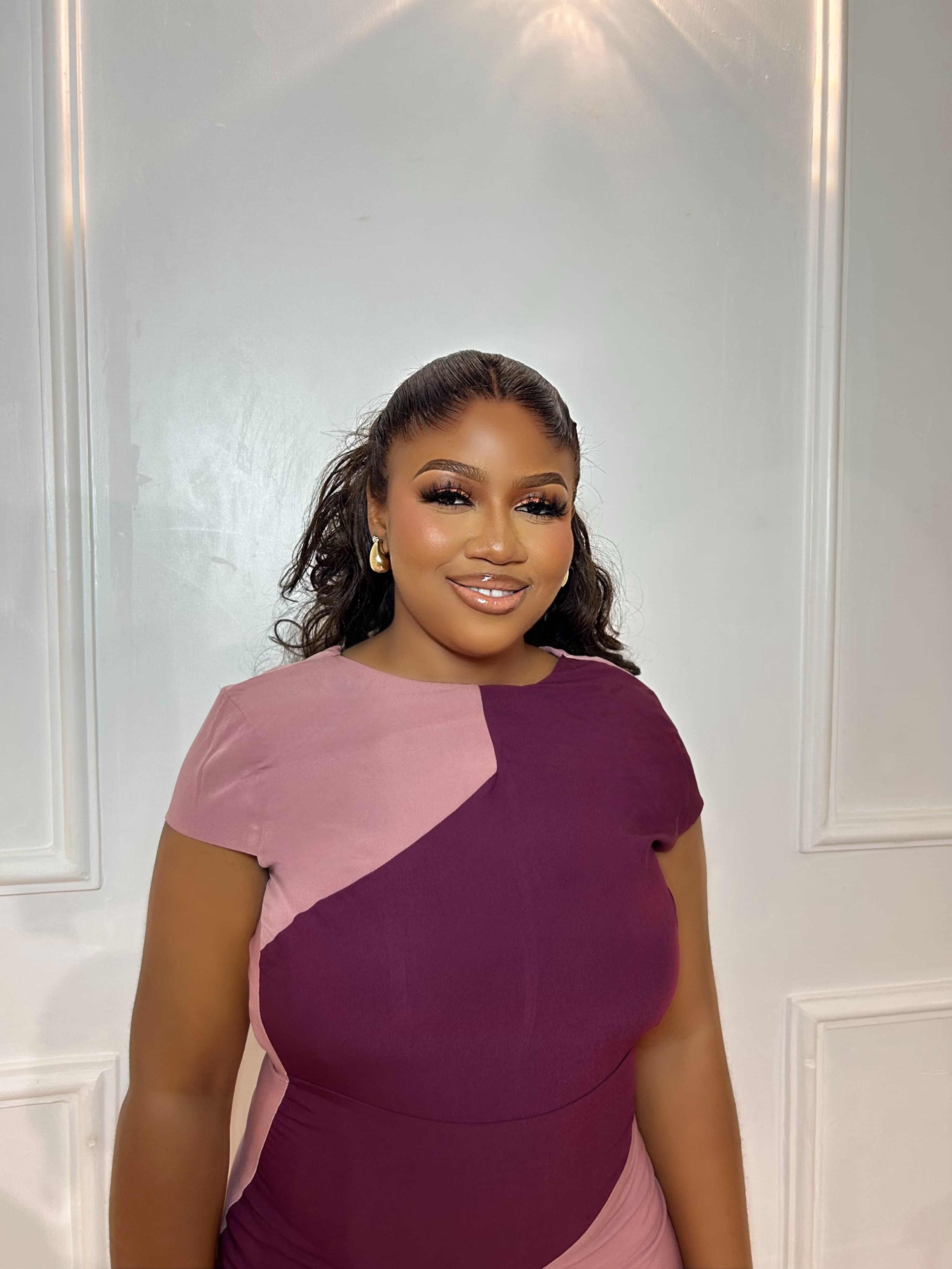 Shalom Ohuegbe smiling, wearing a plum and pink dress